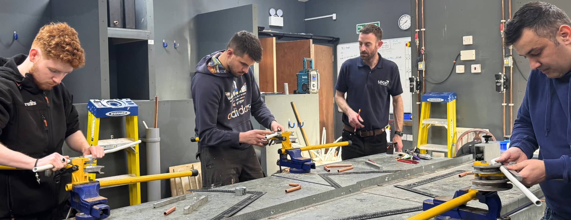 plumbing trainer help a group of students bend pipe and retrain as a plumber