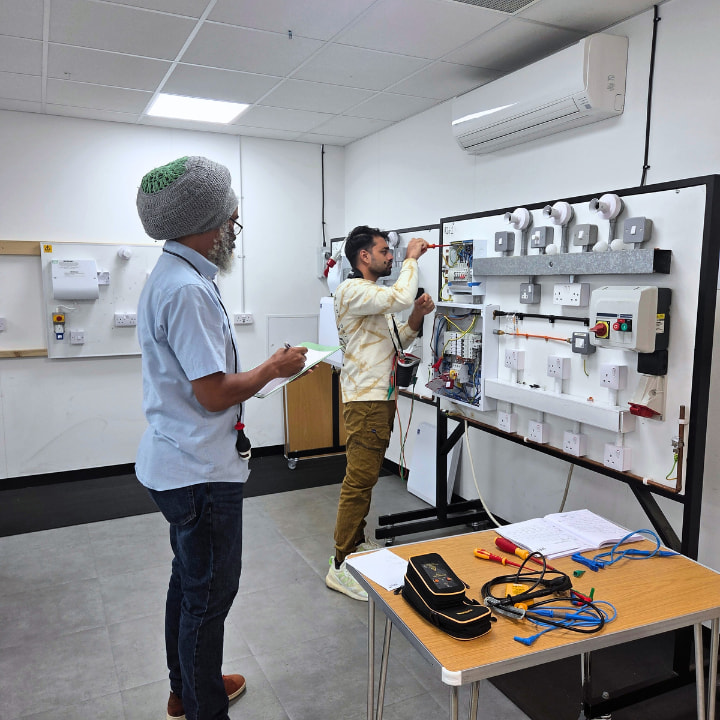 A Logic4training initial inspection and testing electrical trainer marking their student whilst practicing initial inspection