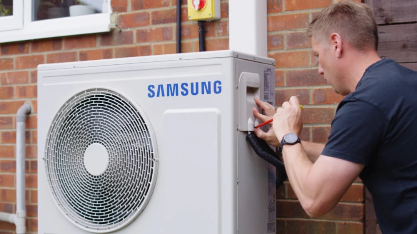 A qualified air source heat pump installer working on a air source heat pump