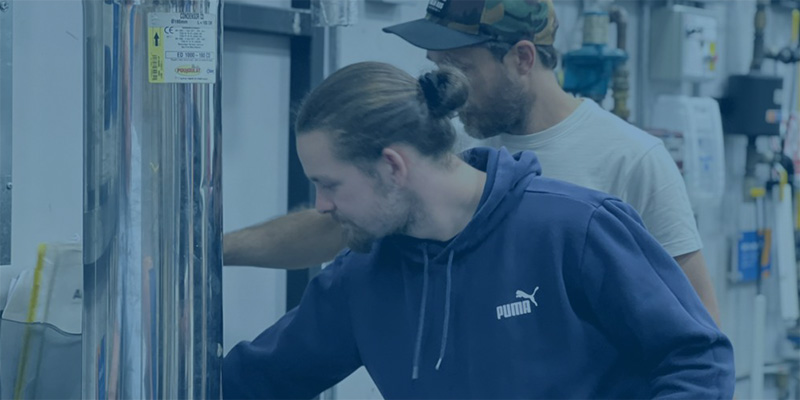 man in hat and white tshirt and man with blue hoody with arms folded