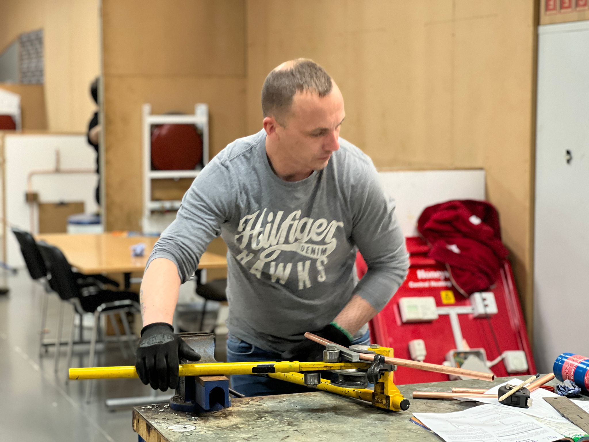man bending pipe on a work bench