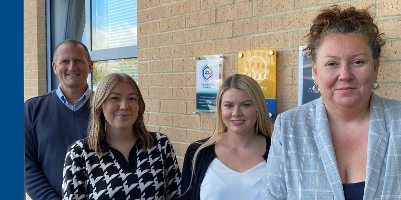 man and three women standing in front of a brick wall.
