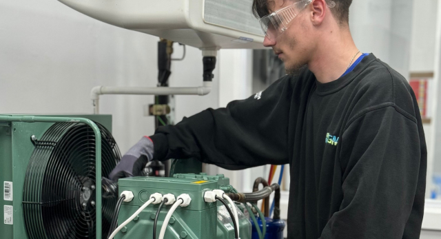 a trainee refrigeration engineer working on an appliance after contemplating the trades vs university