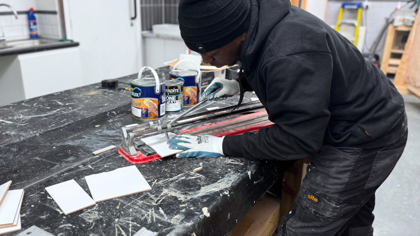 A Logic4training essential site skills student cutting a tile so that they can use it in their tiling training