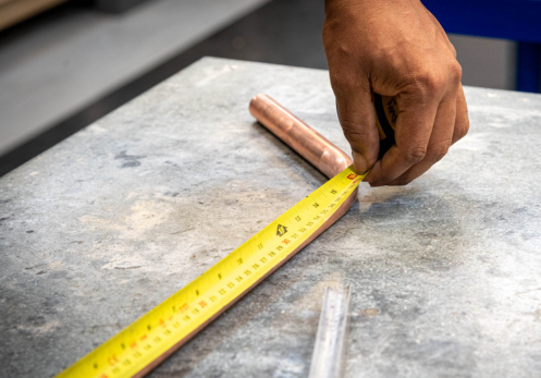 person measuring a pipe with a tape measure