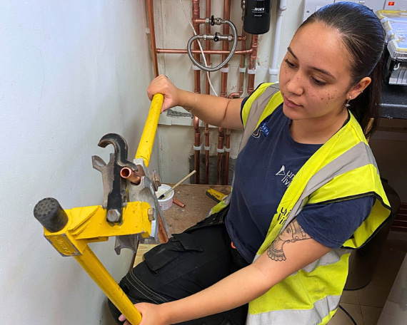 female plumbing student bending some pipe