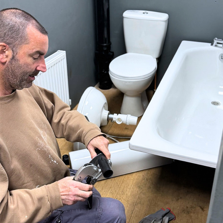 A Logic4training NVQ level 2 plumbing student cutting some waste pipe