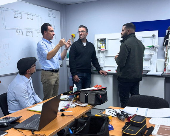 A Logic4training trainer with electrical students going through the 18th edition wiring regulations