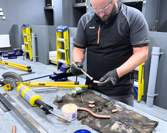 A Logic4training student using flux on a copper pipe inline with the Water Regulations