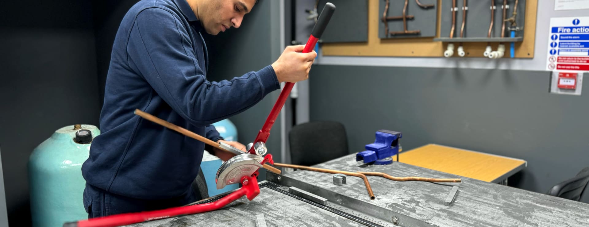 Gas apprentice bending some copper pipe in-person at a training centre