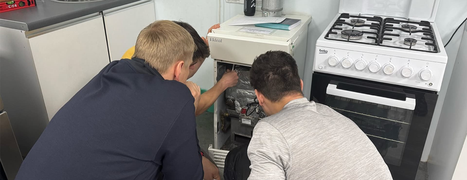 a group of gas engineer students working on a gas appliance