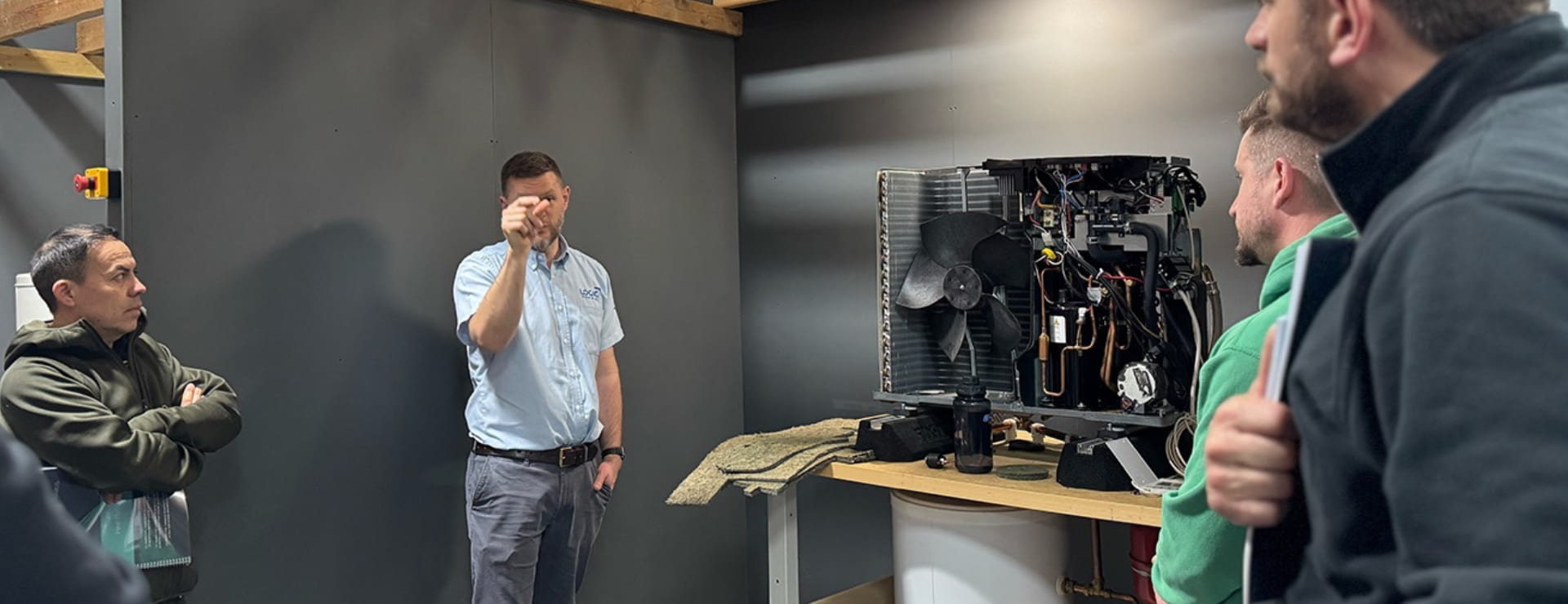air source heat pump trainer standing next to a heat pump whilst explaining it to their class