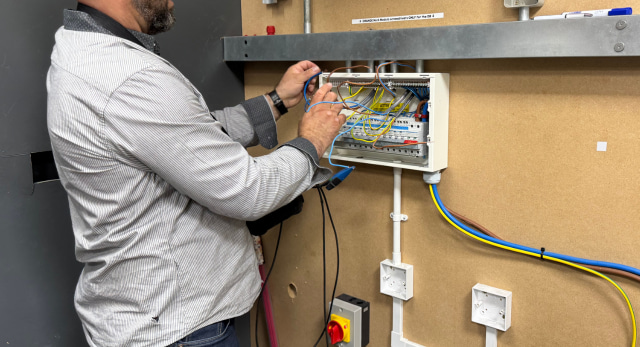 electrical student checking the live wire colour as well as the other wires in a consumer unit