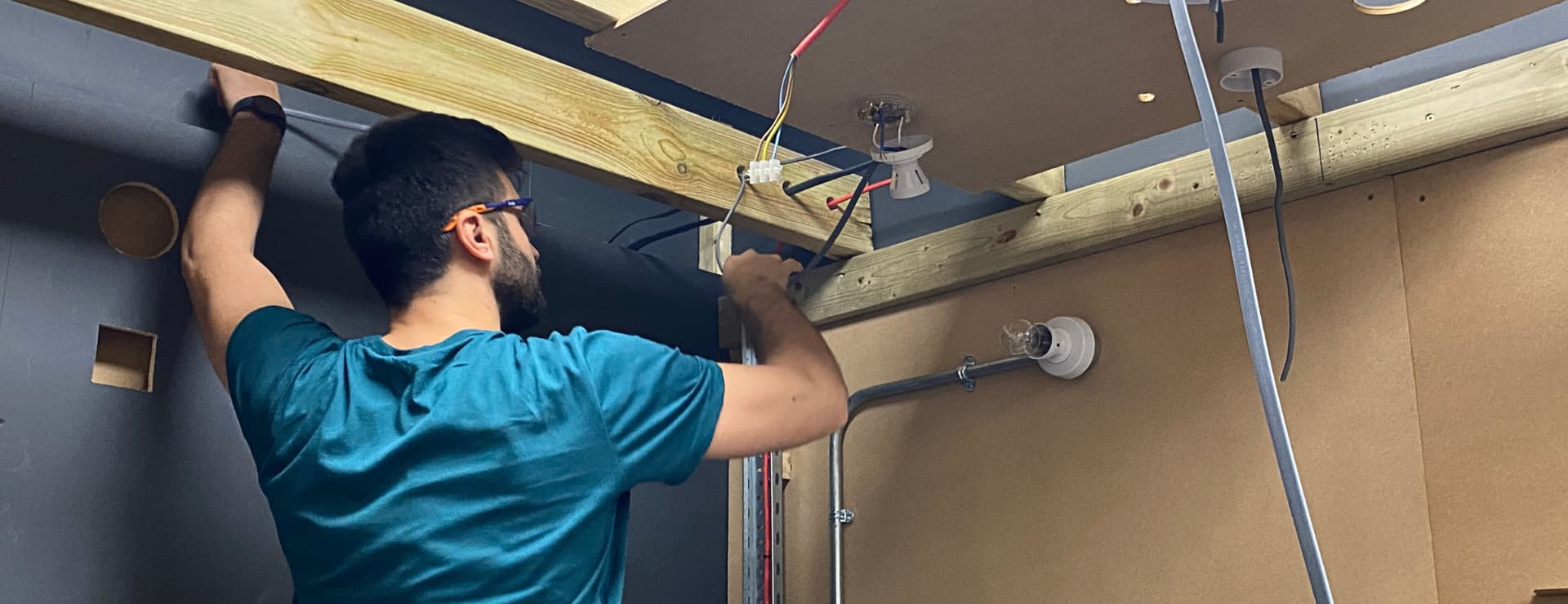 electrical student running some cable with the different coloured wires being exposed