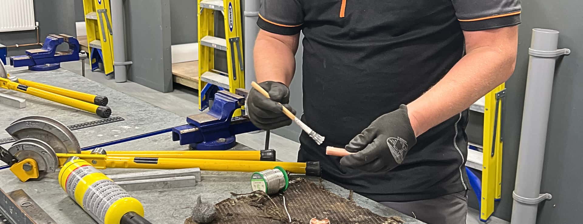 plumbing student applying flux to a copper fitting to complete a plumbing job
