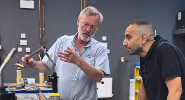 a plumbing trainer heating the solder on a copper pipe and explaining its risk that may result in RIDDOR reporting
