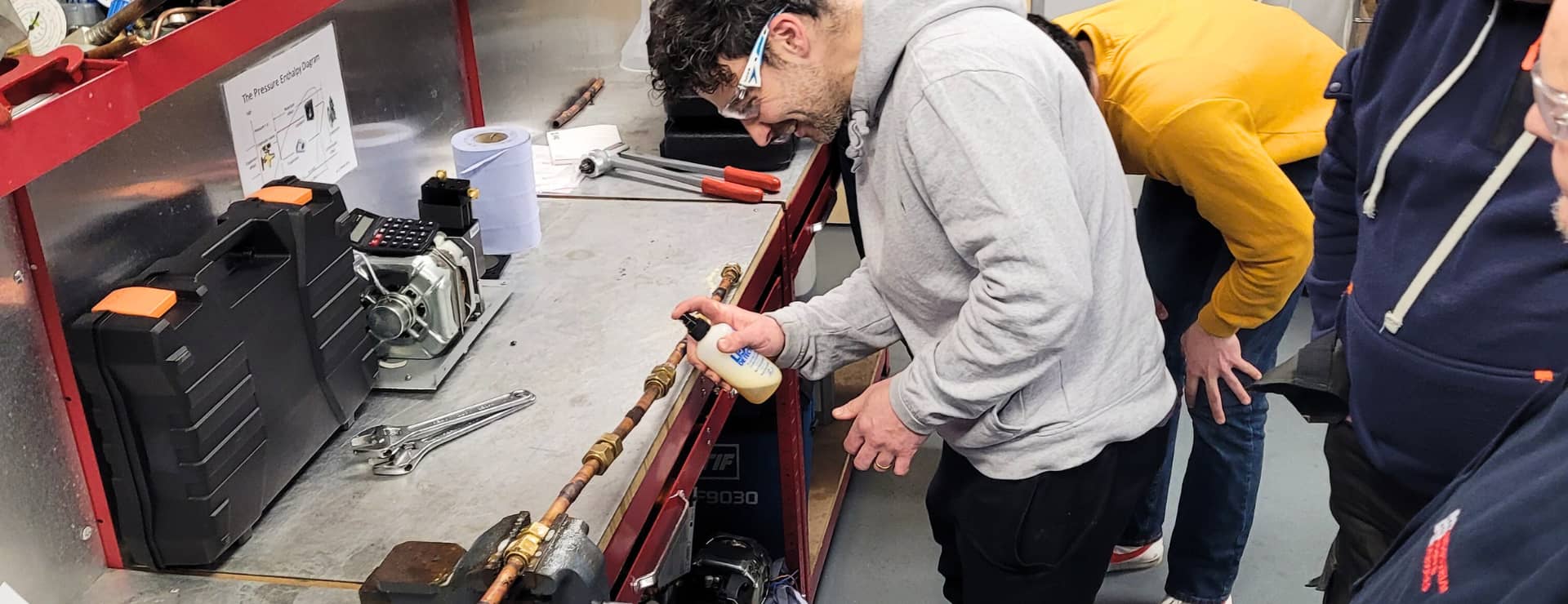 F-Gas student checking pipework for a leak of f-gas