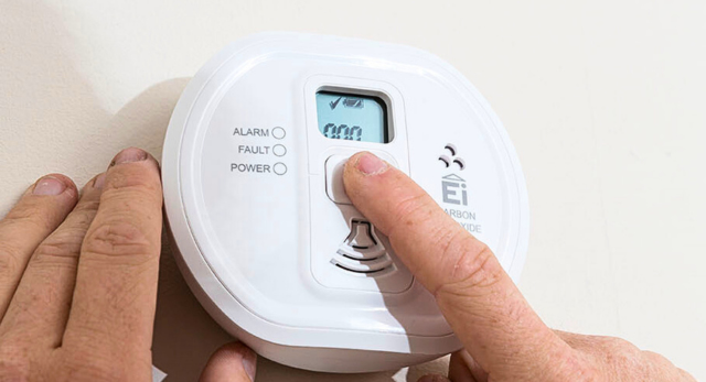 person testing a carbon monoxide alarm