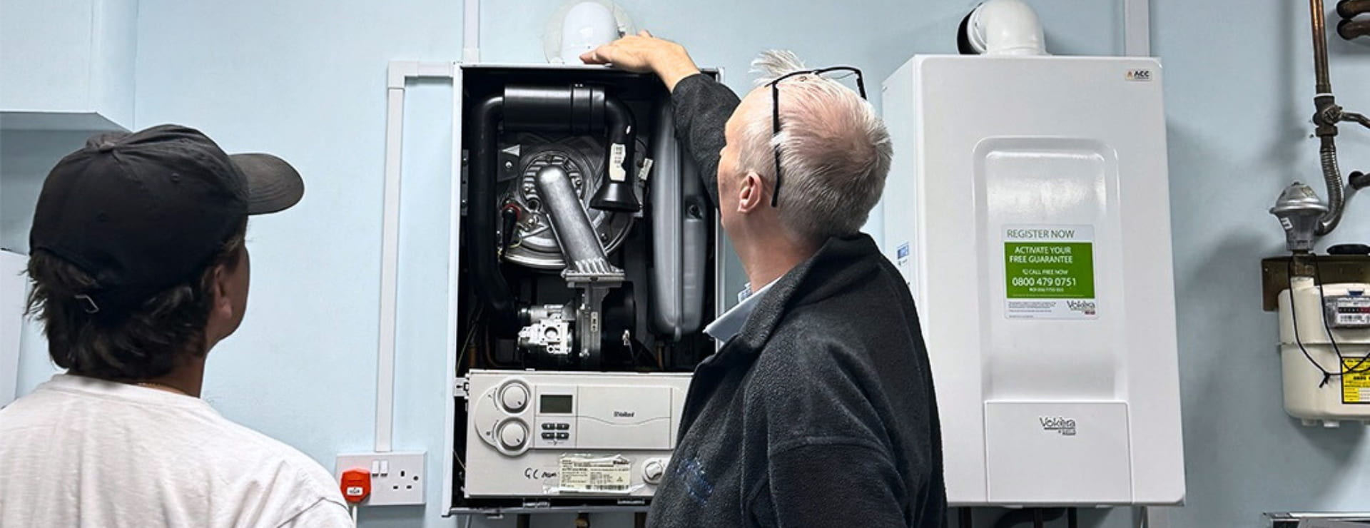Heating service trainee and engineer working on a boiler