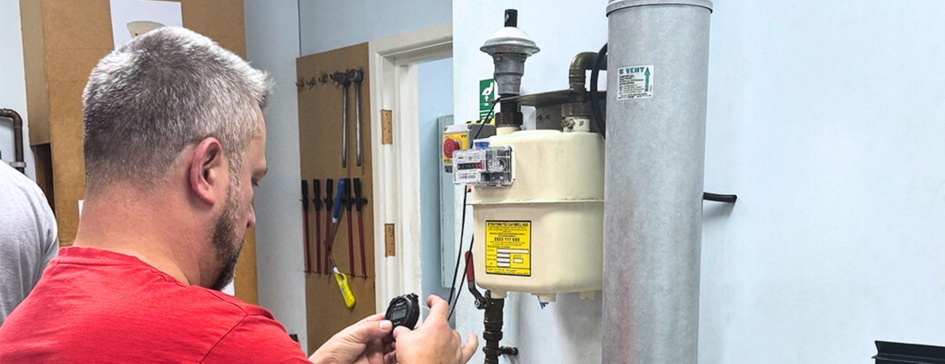 trainee gas engineer performing a heating service on the gas meter