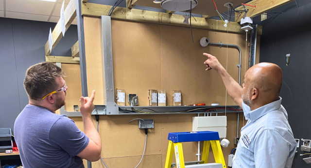A Logic4training electrical student and trainer talking through a training installation and if it follows the wiring regulations