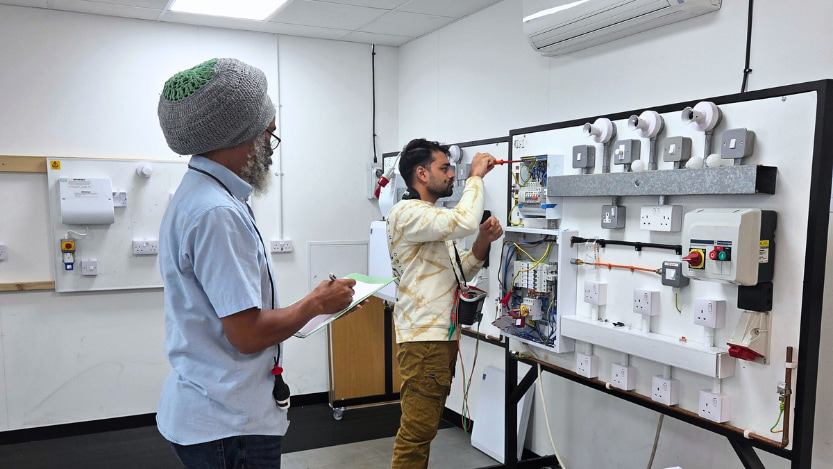 A Logic4training electrical student carrying out inspection, testing, and commissioning under supervision from a Logic4training electrical trainer