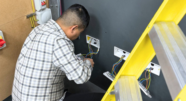 An Logic4training student changing some electrical sockets before filling out a Minor Electrical Installation Works Certificate