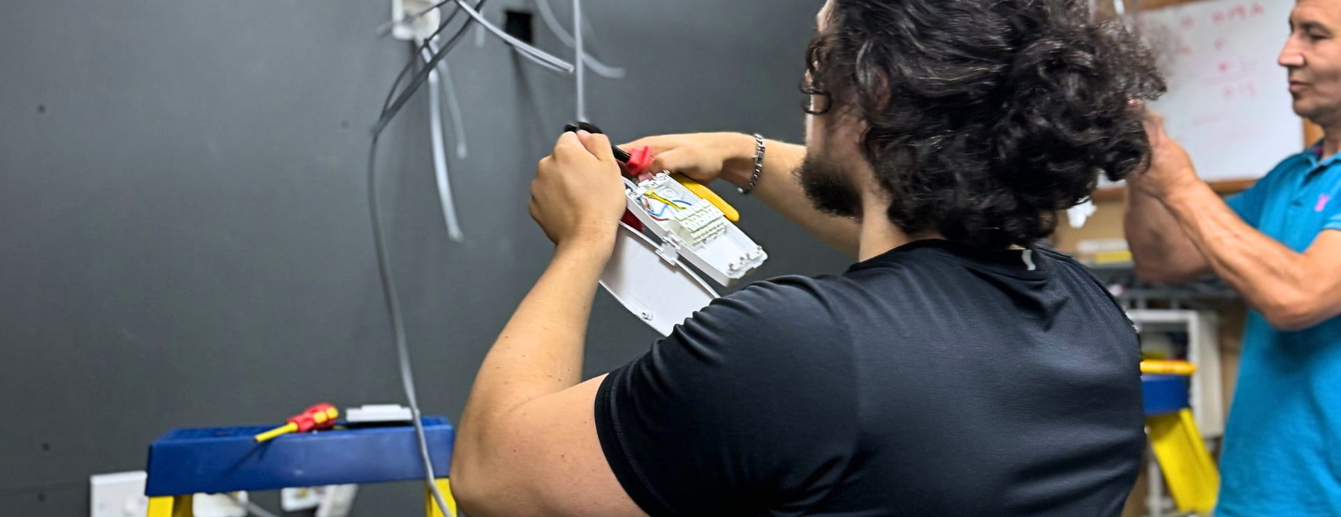 An electrical student carrying out minor electrical work before filling out a Minor Electrical Installation Works Certificate