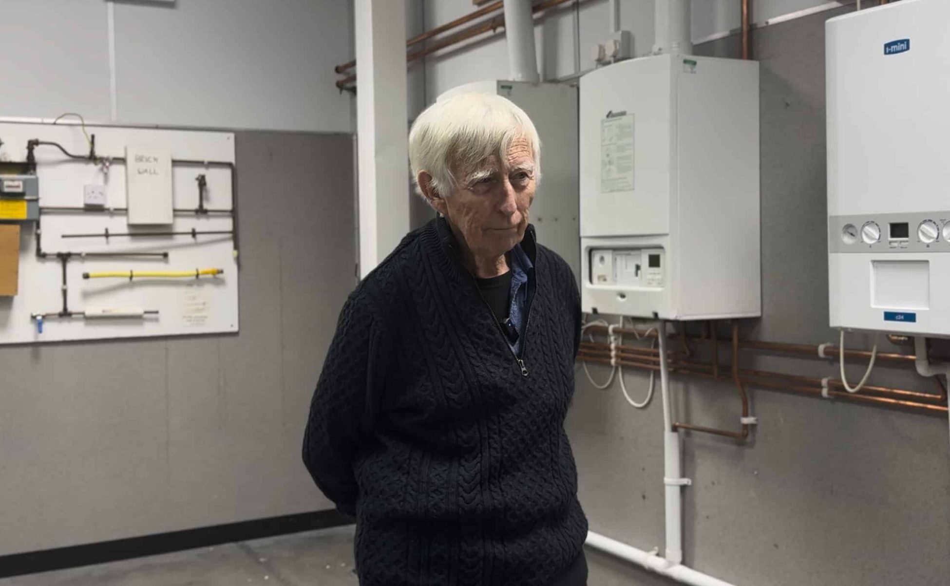 old man stand in gas workshop facing camera