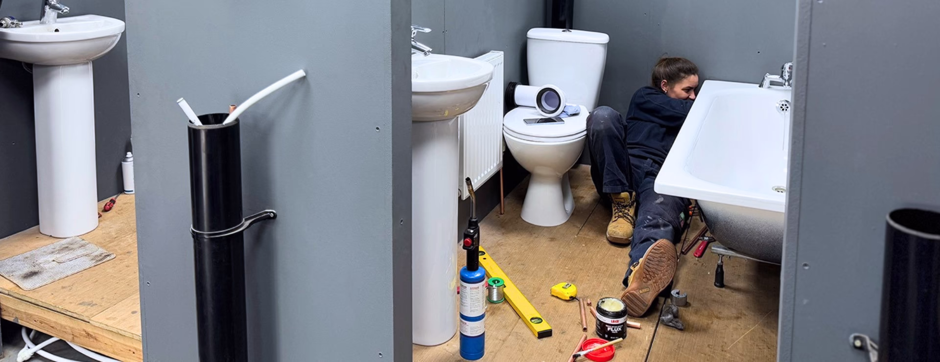 A Logic4training gas engineer apprentice working in a bathroom rig as part of their plumbing training