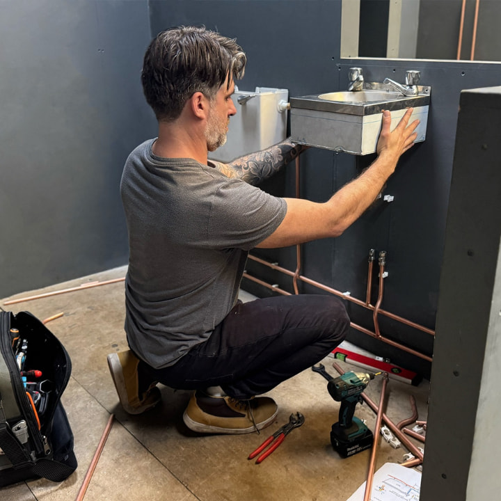 A level 2 diploma in plumbing and heating student fixing a sink to a wall as part of their training