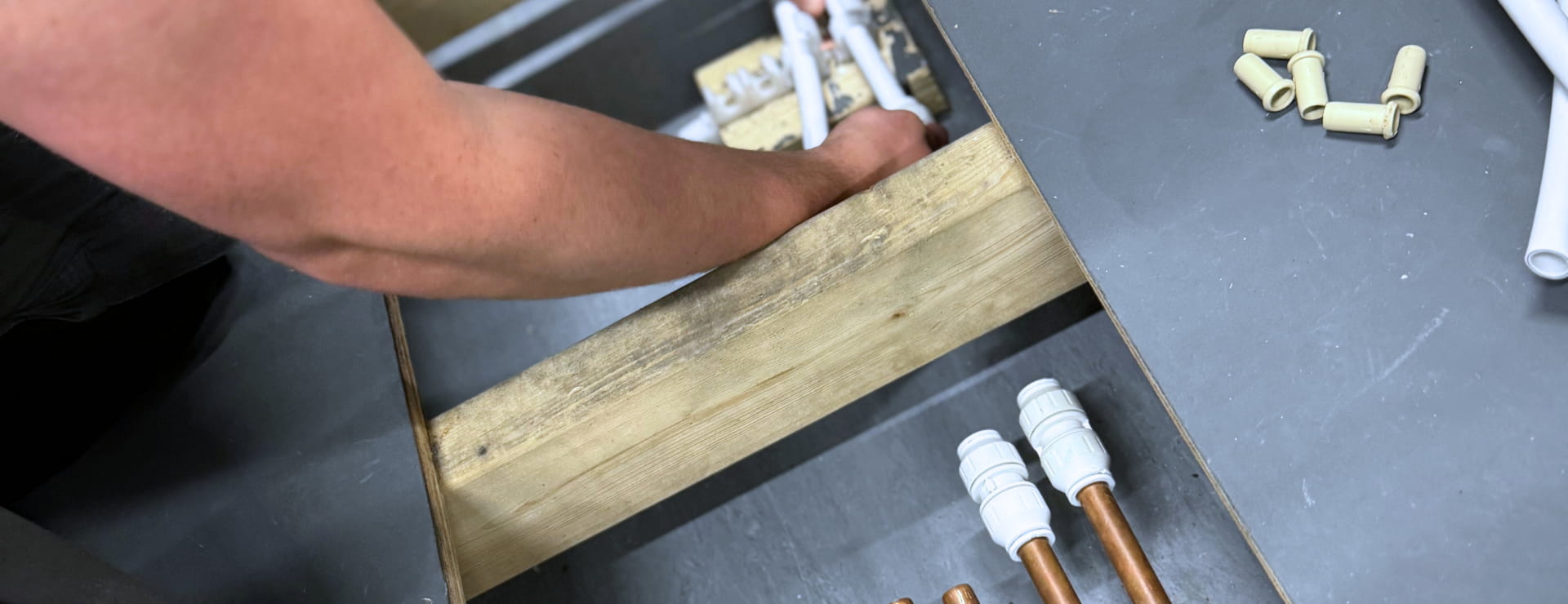 A Logic4training Plumbing Level 2 NVQ candidate fitting pipes under the floor
