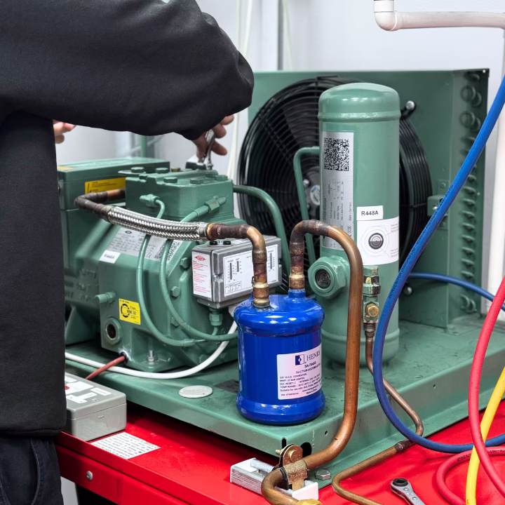 A person completing the Level 3 F-Gas qualification by training on an air conditioning rig
