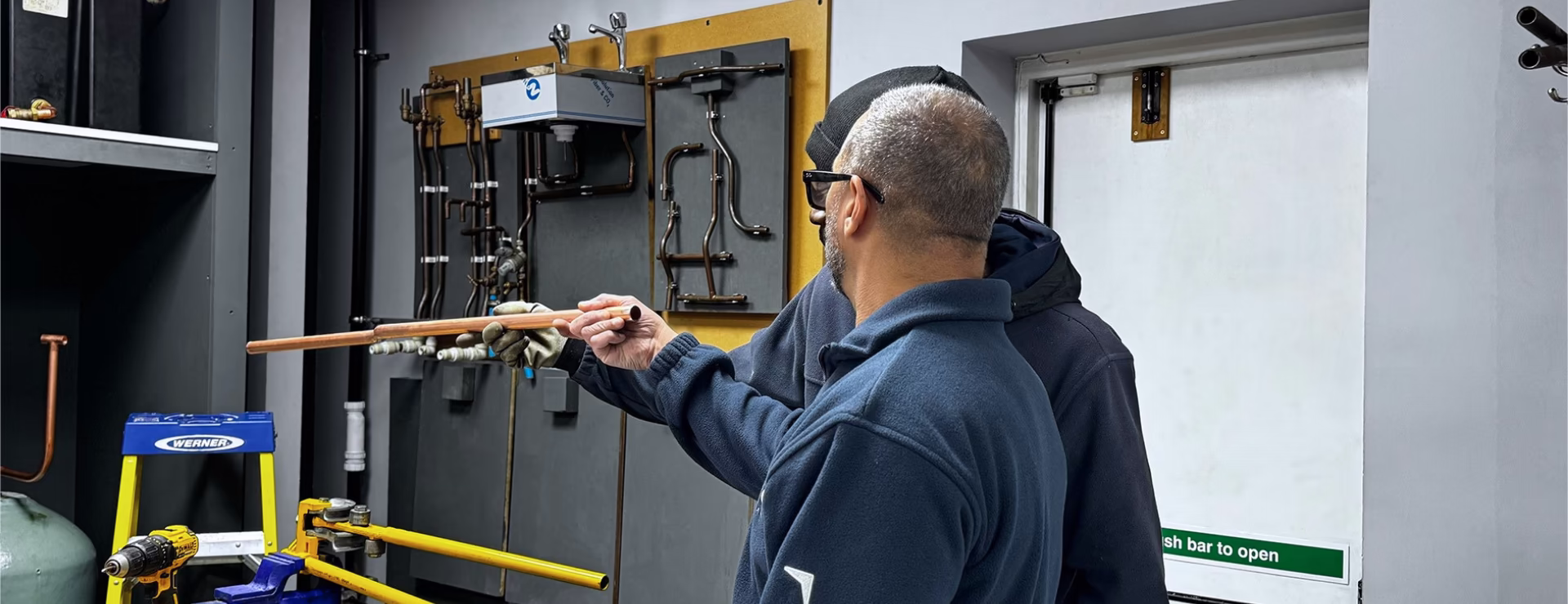 A plumbing trainer and student looking at copper pipe whilst on a London based plumbing course