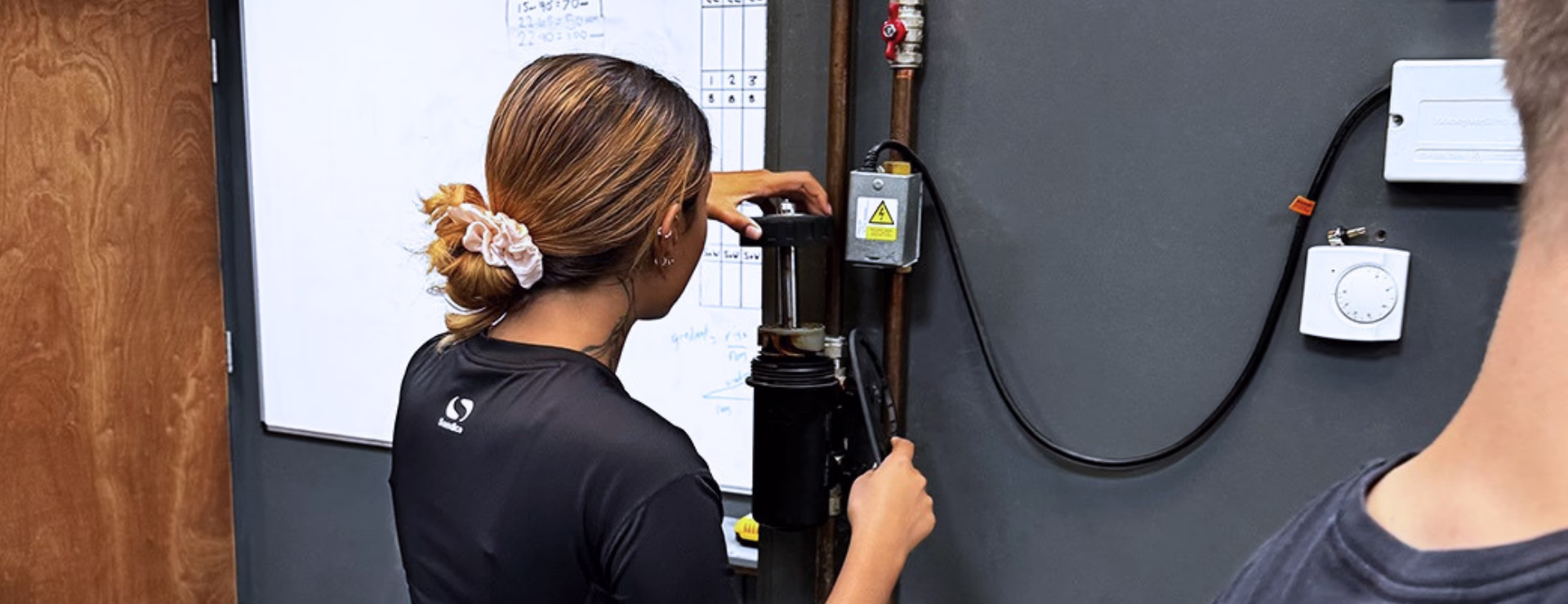 A woman learning how to clean a mag clean as part of their plumbing course