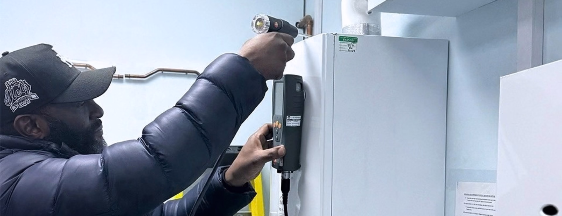 A man using a flue analyser to perform a combustion analysis on the boiler