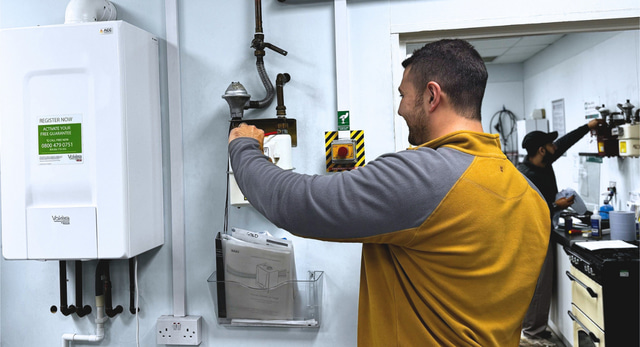 A plumber learning gas by working on a gas meter in a workshop